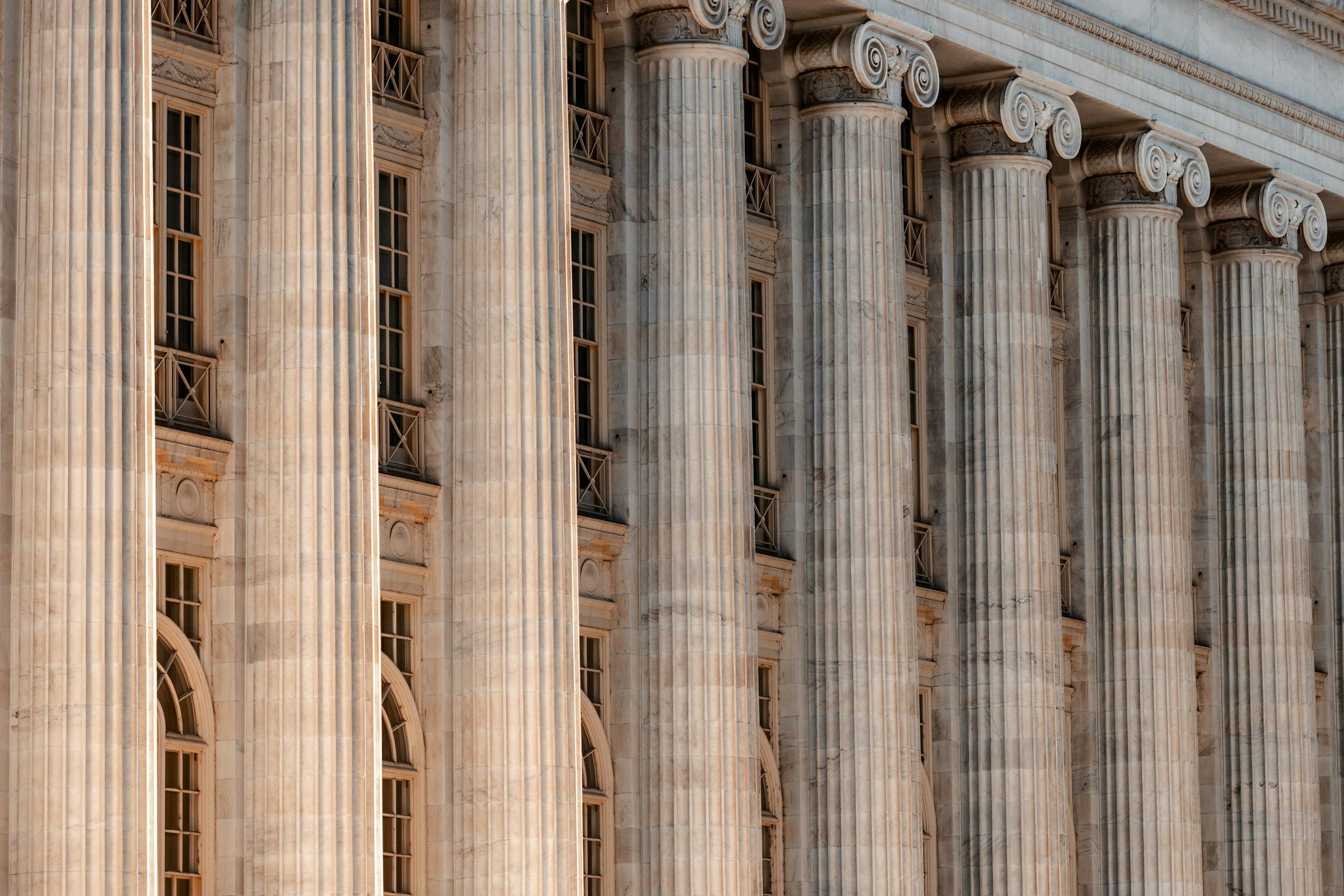 The classical stone columns of a courthouse portico, photographed from below.